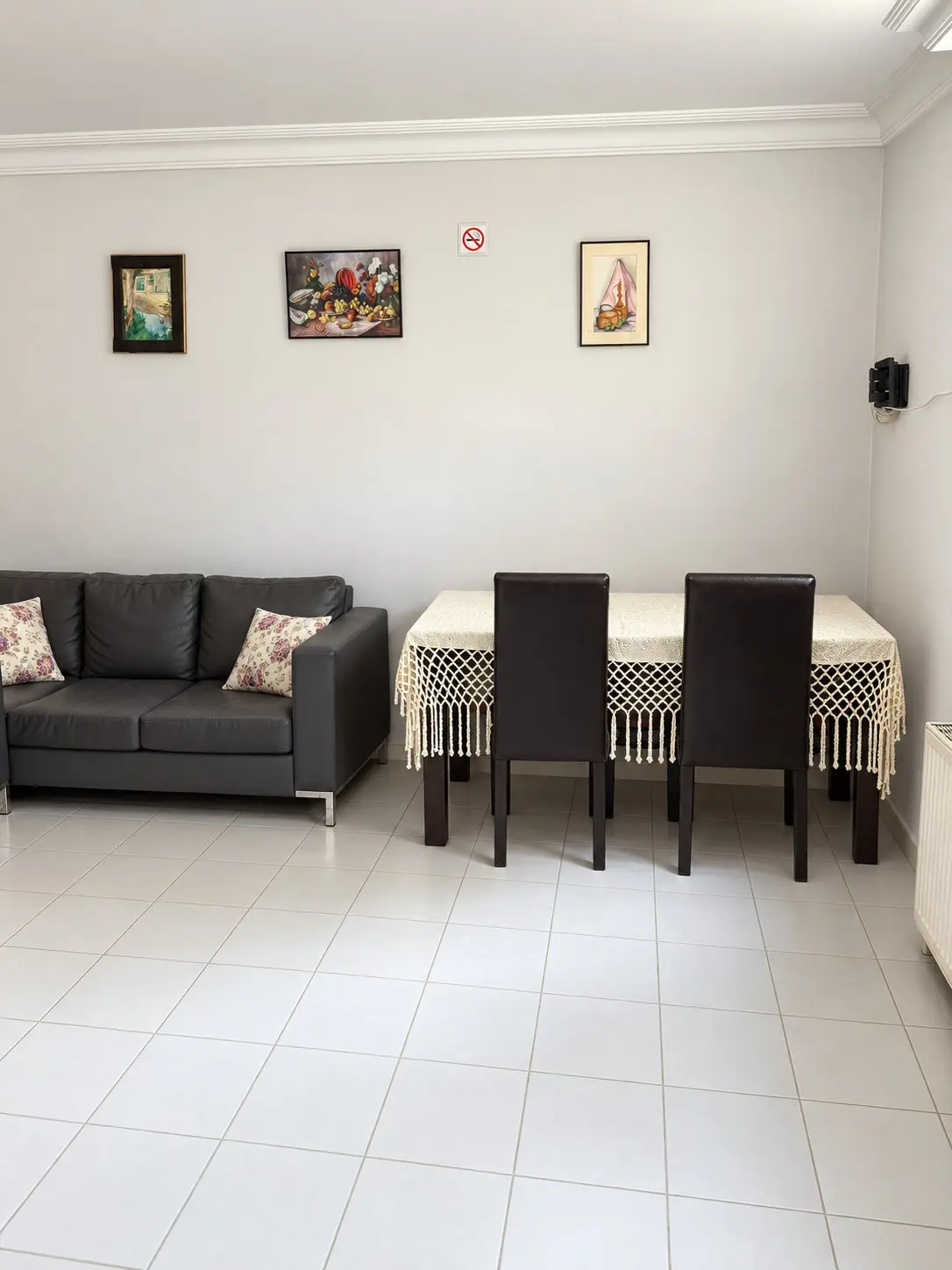 Salonda dantel örtülü yemek masası, sandalyeler ve yanında kanepe